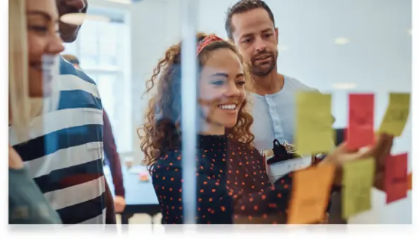 Advisory-led Team of colleagues collaborating with sticky notes on a glass wall during a brainstorming session.