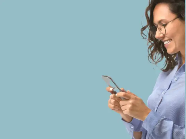 Woman in glasses using a smartphone against a plain blue background.