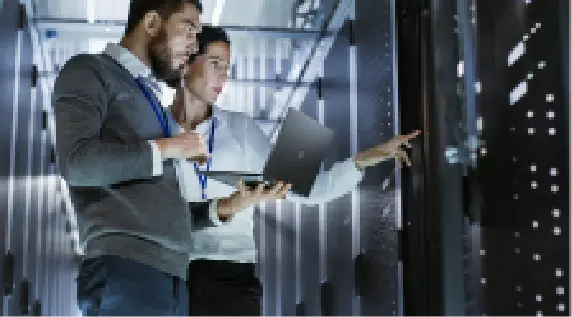 Assessment-focused Two IT professionals analyzing data servers in a data center with a laptop.